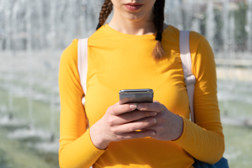 Pabo-studente die op haar smartphone de online theorieuitleg voor de LKT-rekentoets bekijkt op de leeromgeving van Pabo Rekenacademy.